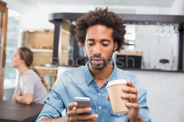 Handsome man sending a text drinking coffee Stock photo © wavebreak_media