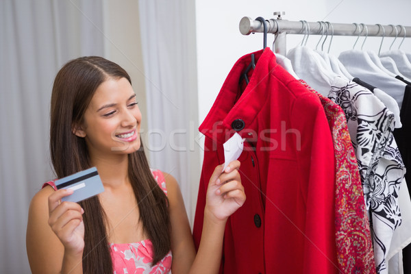 Smiling woman looking at red coat and holding credit card Stock photo © wavebreak_media