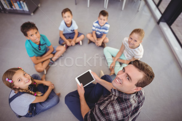 Stock photo: Overhead view of teacher and schoolkids using digital tablet in library