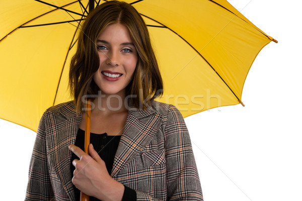 Portrait of young woman holding umbrella while standing against white background Stock photo © wavebreak_media