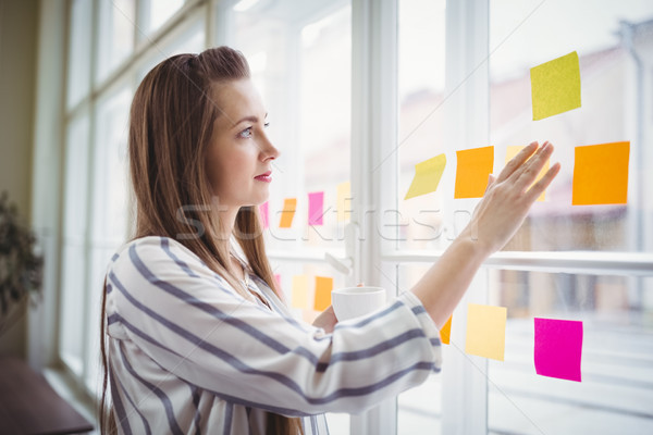 Fiatal üzletasszony néz tapadó jegyzetek ablak Stock fotó © wavebreak_media