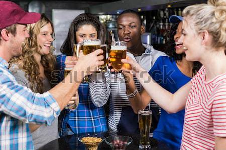 Friends toasting glasses of beer at bar counter Stock photo © wavebreak_media