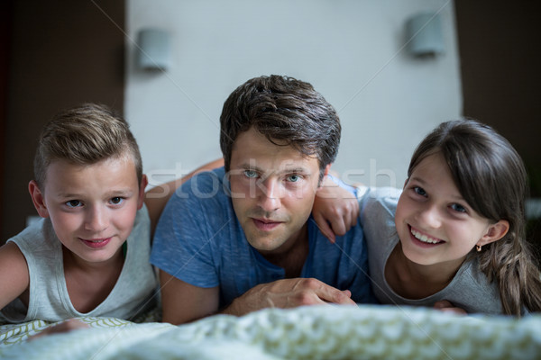 Portrait of father and kids lying in bedroom Stock photo © wavebreak_media