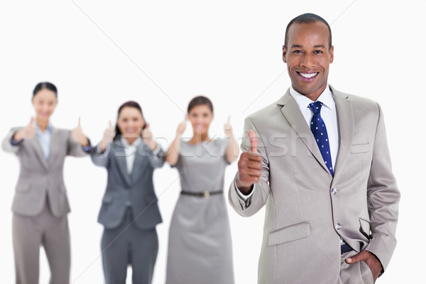 Happy businessman with a hand in his pocket and approving with co-workers in the background with thu Stock photo © wavebreak_media