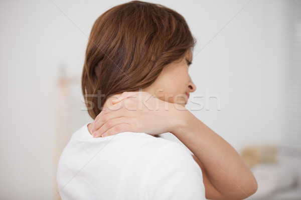 Brown-haired woman massaging her painful neck in a room Stock photo © wavebreak_media