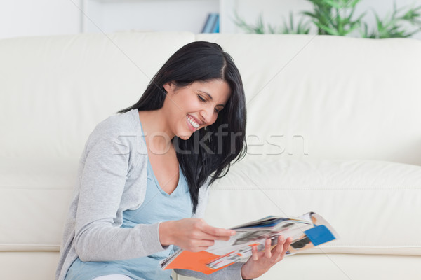 Smiling woman sitting as she reads a magazine in a living room Stock photo © wavebreak_media