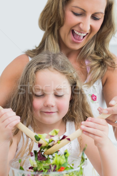 Stock photo: Close up of smiling mother and daughter mixing vegetable salad