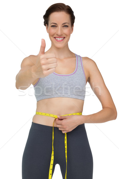 Fit woman measuring waist while gesturing thumbs up Stock photo © wavebreak_media