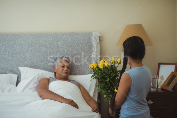 Stock photo: Granddaughter giving flowers to grandmother in bed room