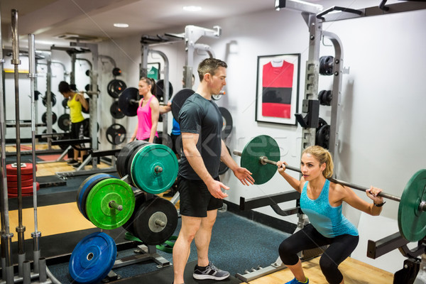 Stock photo: Fit woman lifting heavy barbell in weights room