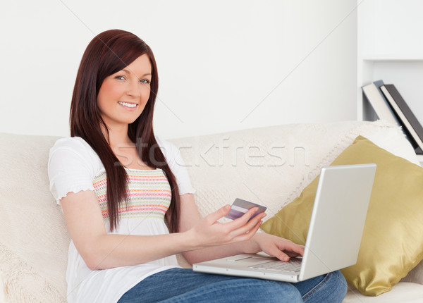 Stock photo: Beautiful woman sitting on a sofa is going to make a payment on the internet in her apartment 
