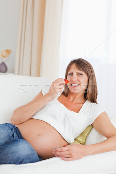 Belle femme enceinte manger fraises canapé sourire [[stock_photo]] © wavebreak_media