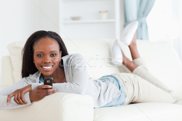 Stock photo: Smiling woman texting on sofa