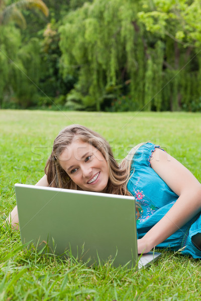 Jeune femme magnifique sourire côté utilisant un ordinateur portable [[stock_photo]] © wavebreak_media