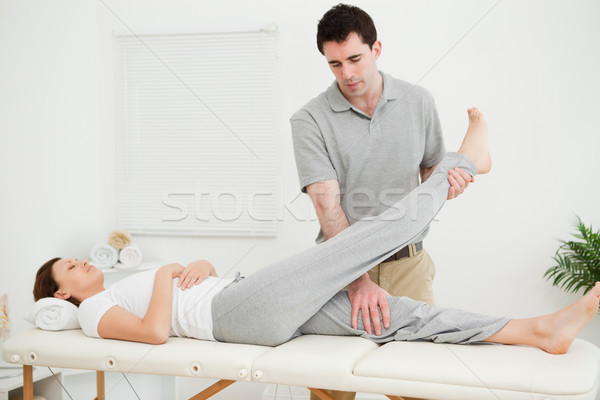 Brunette physiotherapist raising the leg of a patient in a room Stock photo © wavebreak_media