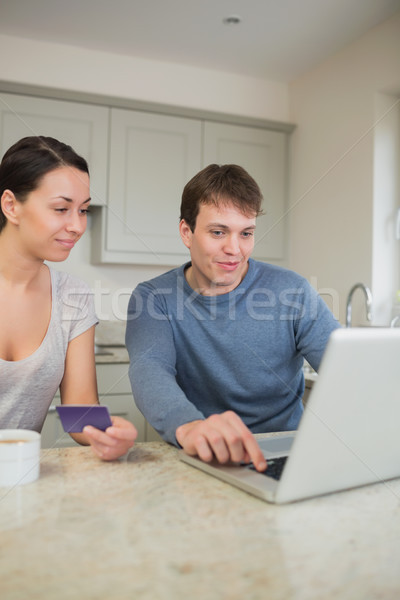 Two people sitting in the kitchen purchasing online on laptop in kitchen Stock photo © wavebreak_media