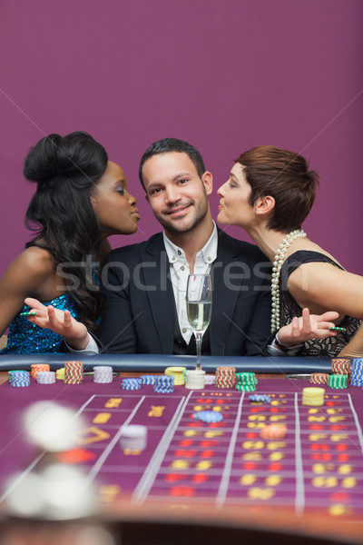 Women kissing man on either cheek in casino Stock photo © wavebreak_media