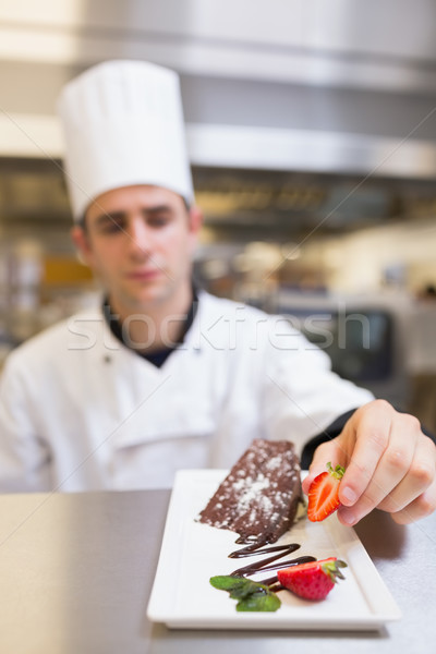 Chef putting a strawberry with the cake on plate in the kitchen Stock photo © wavebreak_media