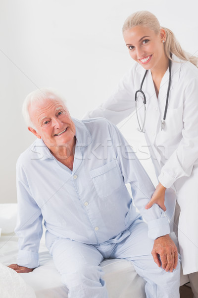 Smiling doctor helping man to sit up Stock photo © wavebreak_media