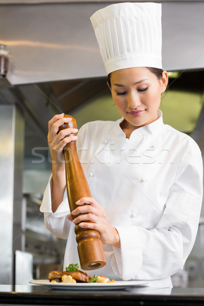 Female cook grinding pepper on food in kitchen Stock photo © wavebreak_media