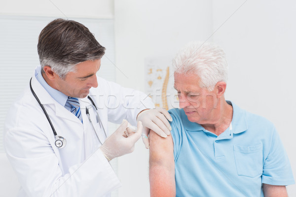 Doctor injecting senior patient in clinic Stock photo © wavebreak_media