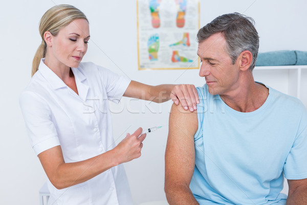 Stock photo: Doctor doing an injection to her patient 