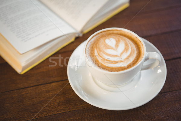 Cup of cappuccino with coffee art next to opened book Stock photo © wavebreak_media