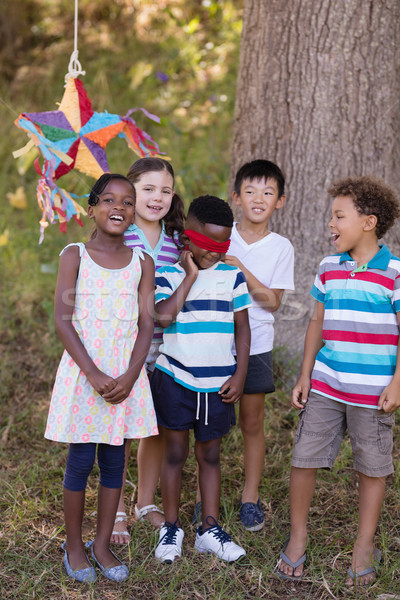 Stock photo: Friends standing with blindfolded boy on grassy field at campsite