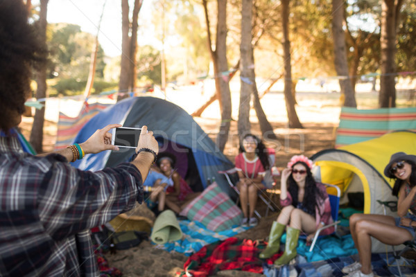 Man photographing smiling friends through mobile phone Stock photo © wavebreak_media