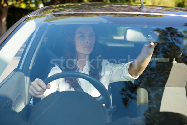 Femeie uita vedere din spate oglindă conducere maşină Imagine de stoc © wavebreak_media