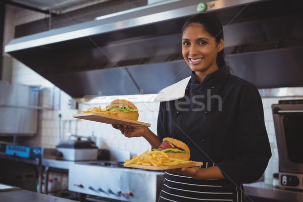 Stock photo: Portrait of waitress with French fries and burger in cafe