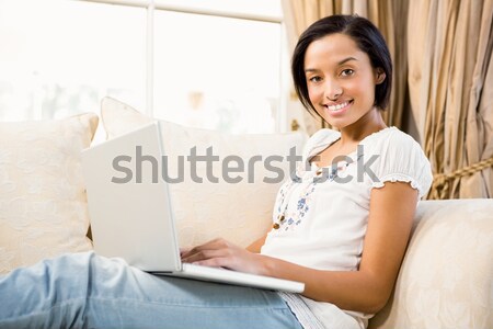 Foto stock: Sorridente · morena · usando · laptop · sofá · casa · computador