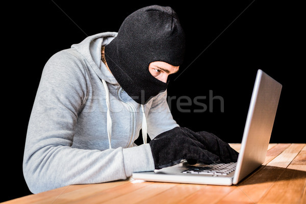 Focused thief with hood typing on laptop Stock photo © wavebreak_media