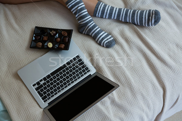Low section of woman relaxing with chocolates and laptop on bed Stock photo © wavebreak_media