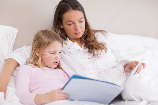 Cute girl reading a book with her mother in a bedroom Stock photo © wavebreak_media