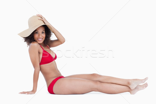 Smiling woman in beachwear sitting down against a white background Stock photo © wavebreak_media
