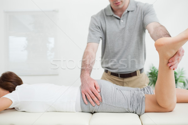 Stock photo: Woman lying while being stretched by a doctor in a room