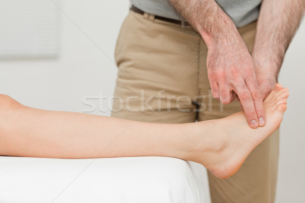 Stock photo: Fingers of a physiotherapist touching a foot in a room