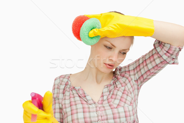 Young woman wiping her forehead while holding sponges against white background Stock photo © wavebreak_media