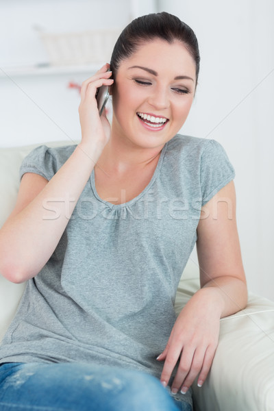 Riendo mujer sesión sofá salón teléfono Foto stock © wavebreak_media