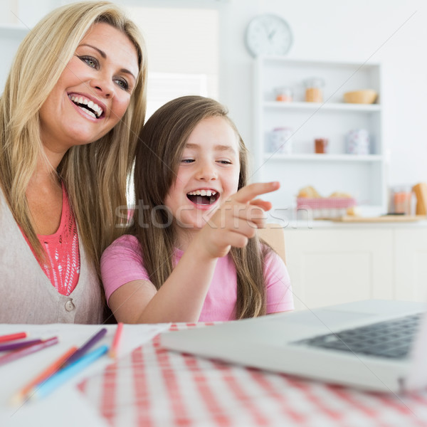 Stock photo: Mother and daughter laughing at laptop in the kitchen