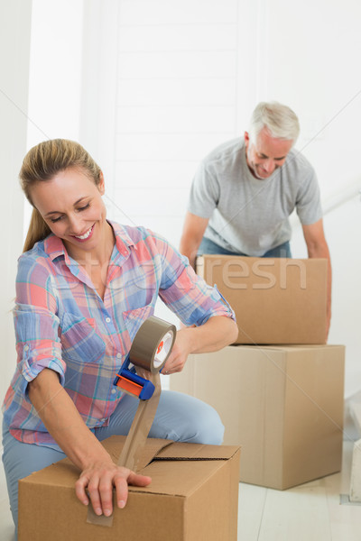 Happy couple sealing cardboard moving boxes Stock photo © wavebreak_media