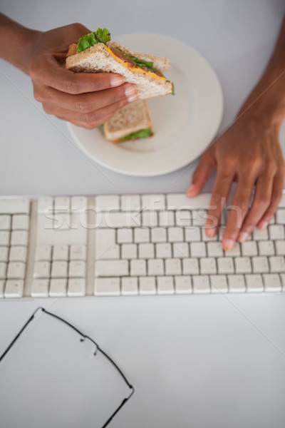 Mujer de negocios comer sándwich escritorio oficina ordenador Foto stock © wavebreak_media