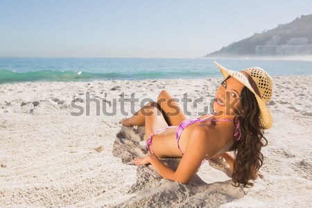 Gorgeous woman sitting on the beach in sunhat applying suncream Stock photo © wavebreak_media