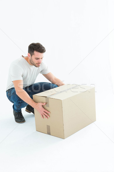 Delivery man crouching while picking cardboard box Stock photo © wavebreak_media