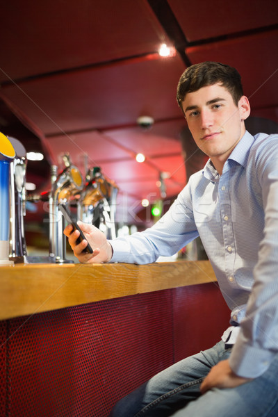 Confident man holding mobile phone at bar counter Stock photo © wavebreak_media