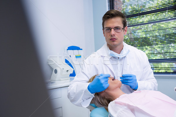 Portrait of dentist cleaning woman teeth while standing against wall Stock photo © wavebreak_media
