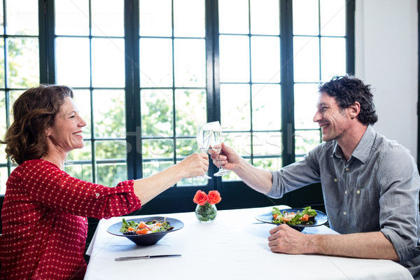 Stock photo: Middle-aged couple toasting champagne flute while having lunch