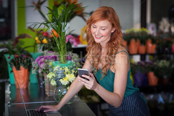 Female florist using mobile phone while using laptop Stock photo © wavebreak_media