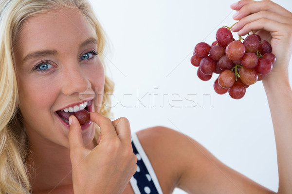 Portrait of beautiful woman eating red grapes Stock photo © wavebreak_media